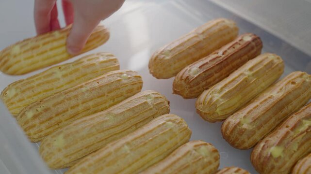 Close-up view of fresh baked eclairs with tempting cream filling, neatly arranged in a bakery display. Perfect image for any dessert or pastry marketing needs.