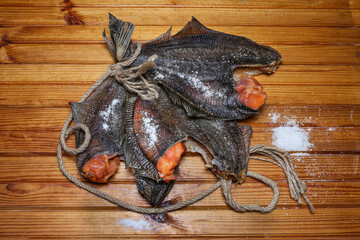 Dried flounder with caviar and salt lies on a wooden board.