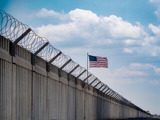 Barbed Wire Fence with American Flag Under Blue Sky