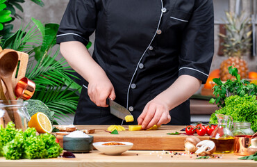 Private Chef cuts yukon gold potatoes into cubes. Cozy kitchen with wooden table, kitchenware, vegetables, herbs and ingredients for cooking. Healthy vegan food, culinary, recipes, food blogging