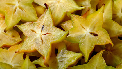 Fototapeta premium Detailed view of fresh starfruit slices, showcasing their star-shaped pattern and bright yellow color. Perfect for healthy food, fruit salads, or tropical concepts. Texture, background.