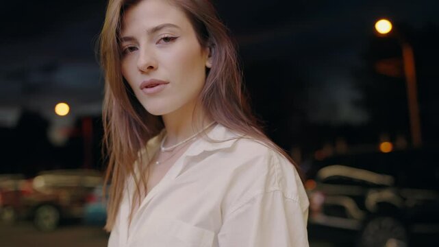 Close-up of an elegant young woman with soft focused city lights illuminating the night behind her. Perfect for themes of urban life, beauty, and contemplation. Elegant Woman Portrait