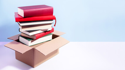 Books in a box ready for donation on blue, copy space. Concept of books donations