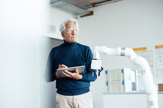 Senior engineer working with robotic arm in a laboratory office