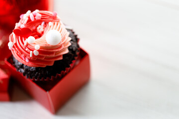 Chocolate cupcake with pink cream and heart shaped sprinkles.