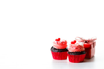 Chocolate cupcakes with pink cream and heart shaped sprinkles.