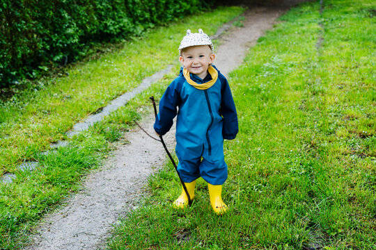 Cheerful child in rain gear exploring outdoors