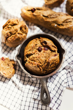 Homemade rye sourdough bread with raisins in a cast iron pan on a kitchen towel, representing traditional Ukrainian baking.