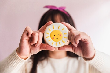 Young confectioner holding sun shaped cookie in hand