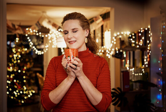 Happy woman having hot chocolate in Christmas at home