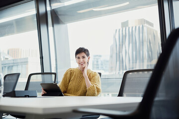 Businesswoman using tablet computer in modern office boardroom