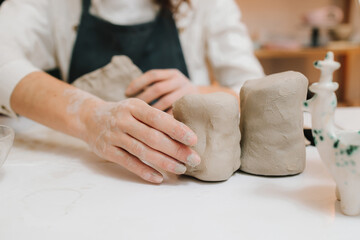 Potter is sculpting wet clay for ceramics products. Hands of a female potter making ceramic clay...