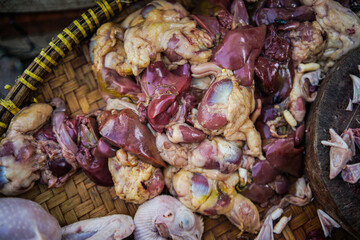 Domestic chickens with claws and liver and gizzards are displayed on a table in the market.