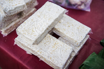 Tempeh made from soybeans is sold in the market wrapped in banana leaves and some are also wrapped in plastic.