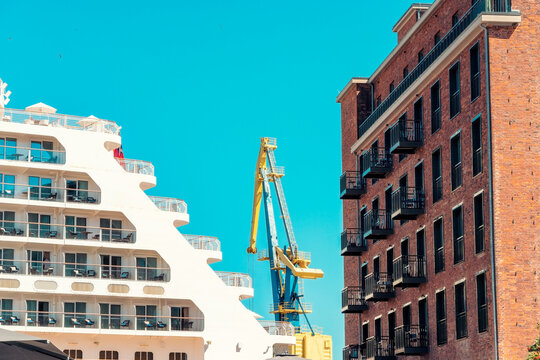 View of a Hanseatic red brick building, a crane, and a cruise ship at the harbor in Wismar, Germany