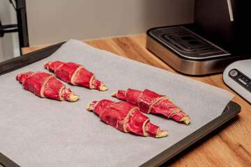 Frozen croissants with raspberry filling on a baking sheet