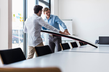 Smiling businessmen examining surfboard in office