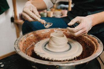Potter sculpts a ceramic mug from clay in the pottery studio. Molding earthenware with potters tools.