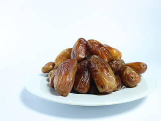 plate of fresh, glossy dates stacked on a white dish isolated on white background