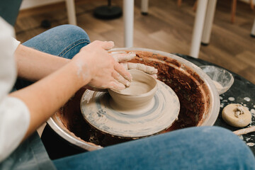 Artisan sculpts a pottery plate on the spinning wheel. Craftswoman is molding porcelain dish in the pottery studio.