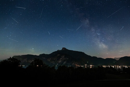 Night view of Schafberg with shooting stars and Milky Way in Mondsee, Austria