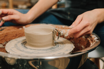 Creating ceramic earthenware on the manufacturing. Artisan forms clay pot with potters tool on the...
