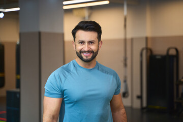 Confident fitness trainer smiling in modern gym