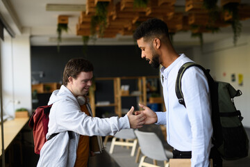 Young man with Down syndrome greeting his teacher in school.