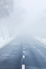 Rural road in winter vanishing in mist, perspective view