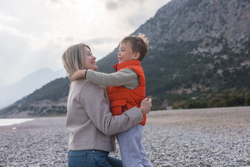 Mother and son enjoy a warm embrace on a winter beach outing