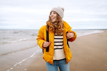 Woman tourist in a yellow jacket posing by the sea in the cold weather. Travelling, lifestyle, adventure