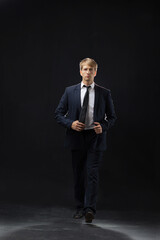 confident man strides forward in a dark suit, exuding authority and professionalism. The low-key,...
