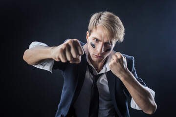 In a dimly lit studio, a man in a navy suit adopts a boxing stance, showcasing strength and...