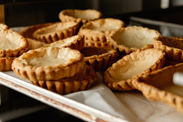Freshly baked pastry shells cooling on a baking tray in a cozy kitchen setting during early morning hours