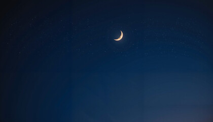 A glowing crescent moon shining in the deep blue night sky, symbolizing the beginning of Ramadan and its spiritual significance.