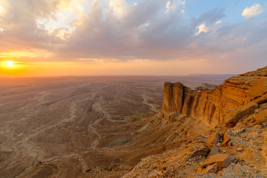 Stunning sunset over the vast desert landscape viewed from the cliffs of the Tuwaiq mountain range in Riyadh, Saudi Arabia, showcasing the beauty and tranquility of nature