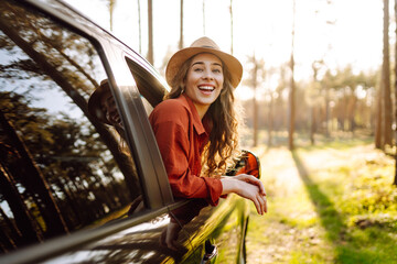 Happy young woman looking out of car window and enjoy travel. Nature, vacation, tourism concept