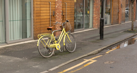Manchester, uk, January 19th 2025 Old fashioned yellow bicycle standing up against a post in a...
