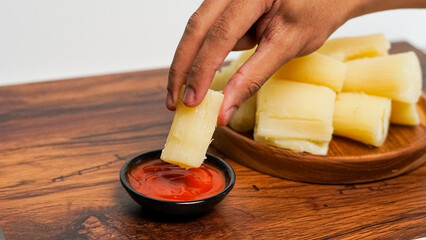 boiled cassava served on a wooden background. with spicy red chili sauce
