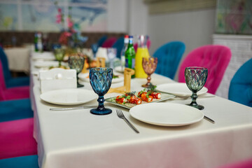 A table with a variety of colorful glasses and plates, and a fork and knife on the table
