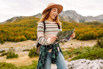 Adventurous woman navigating in with a Topographic Map in the beautiful Mountains. Travel, ...