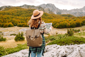 Adventurous woman navigating in with a Topographic Map in the beautiful Mountains. Travel, ...