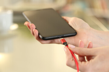 Woman hand plugging charger cable to a smart phone