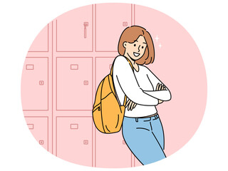 Woman student stands near boxes for personal items in college hallway and looks at screen smiling. Girl student at university or high school rejoices at opportunity to receive quality education.