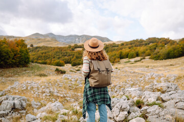 Back view of Woman tourist standing at mountains with backpack admiring landscape. Europe travel....