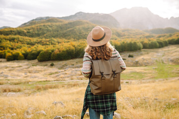 Back view of Woman tourist standing at mountains with backpack admiring landscape. Europe travel....