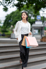 Shopping Delight: A stylish individual descends a staircase, carrying vibrant shopping bags and...