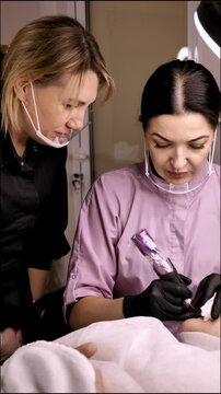 Permanent lip makeup beautiful woman over 50 years old in a beauty salon. A close-up beautician does a tattoo on his face. Vertical, slow mo