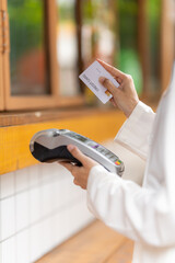 Seamless Transaction: A close-up view of a person's hand paying with a credit card at a sleek,...
