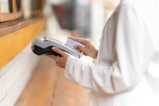 Contactless Transaction: A person, dressed in a crisp white outfit, is captured mid-transaction, using a modern card reader to securely process a payment card.